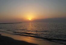 Sunset over calm sea with gentle waves on a sandy beach