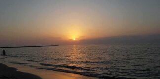 Sunset over calm sea with gentle waves on a sandy beach