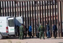 DHS Crackdown: Worst-Of-The-Worst – Or Window Dressing? Border agents escort a group near a tall fence and a patrol van