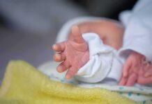 Protective Guardrail Vanishes For Abortion Survivors Newborn hand reaching out on a blanket