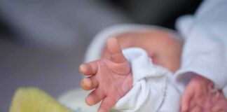 Newborn hand reaching out on a blanket