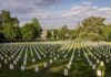 Rows of white headstones in a cemetery under a partly cloudy sky