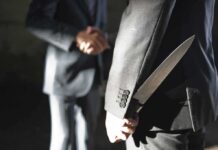 Federal Overreach CRUSHED – Knives Reclassified man in suit hides a knife behind his back while shaking hands