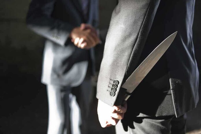 shutterstock_321580841 man in suit hides a knife behind his back while shaking hands