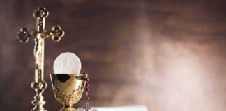 Golden chalice with communion wafer and rosary