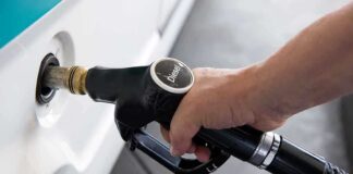 A hand holding a diesel fuel nozzle while refueling a vehicle